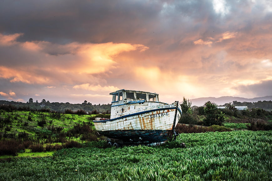 Abandoned Rusty Fishing Boat in Green Field at Sunset