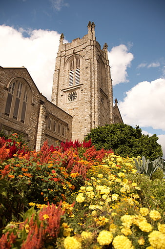 Stone church tower with vibrant flower garden