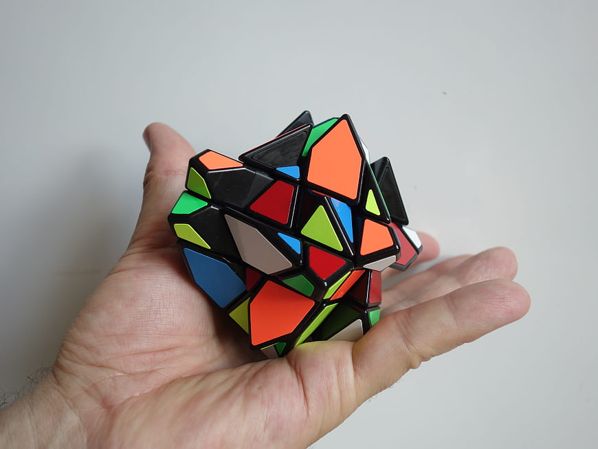 Hand holding scrambled colorful geometric puzzle cube