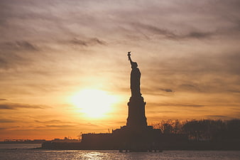 Statue of Liberty Silhouette at Sunset Over Water