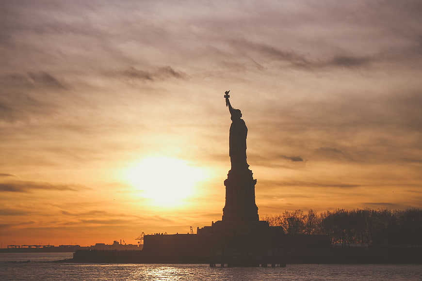 Statue of Liberty Silhouette at Sunset Over Water