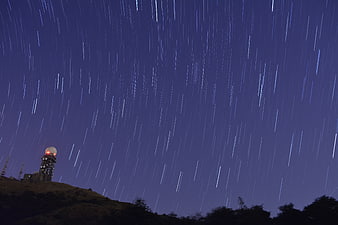 Star trails over radar dome on hilltop at night