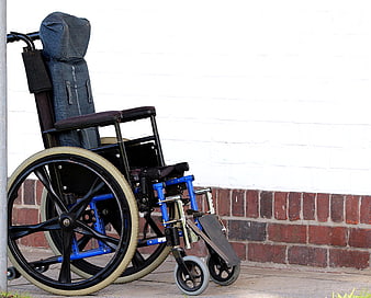 Blue and black wheelchair parked against a white brick wall