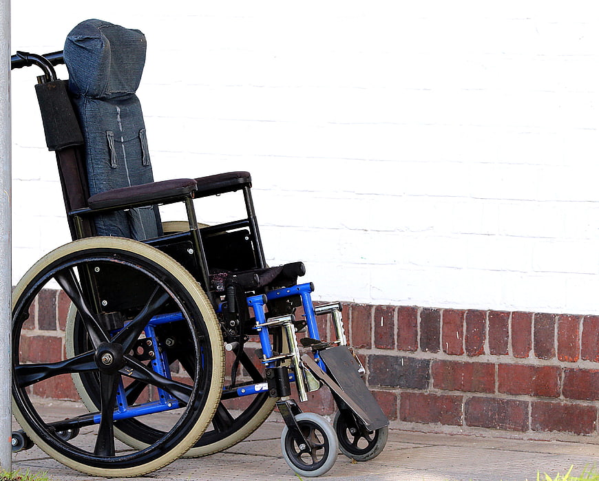 Blue and black wheelchair parked against a white brick wall