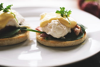 Close-up of Eggs Benedict with Hollandaise Sauce on White Plate