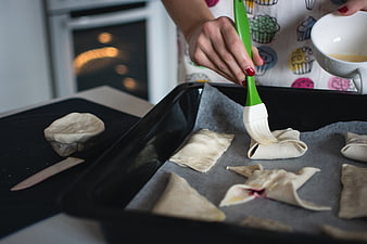 Woman brushing egg wash on strawberry pastries before baking