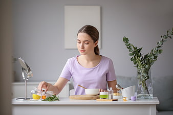 Woman making natural homemade face mask with herbs and oils
