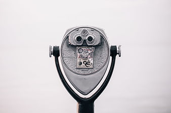 Close-up of silver coin-operated binoculars against white background