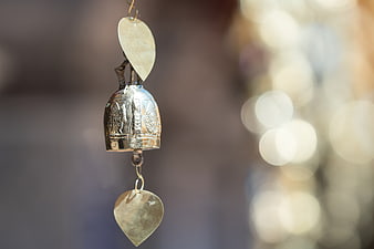 Close-up of ornate silver wishing bell with heart charms