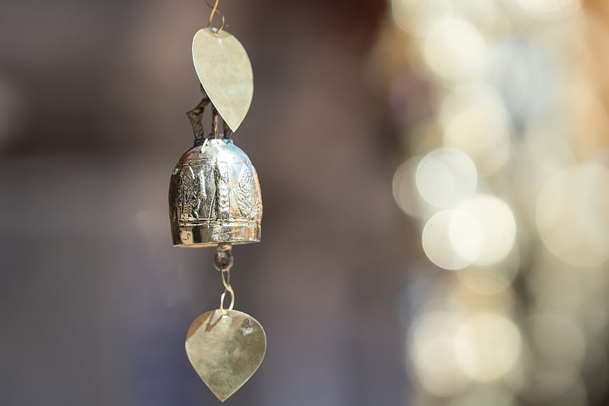 Close-up of ornate silver wishing bell with heart charms