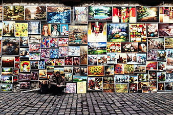 Street Artist Selling Paintings on Cobblestone Road