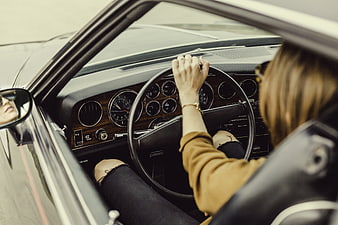 Woman driving vintage car with wood dashboard interior