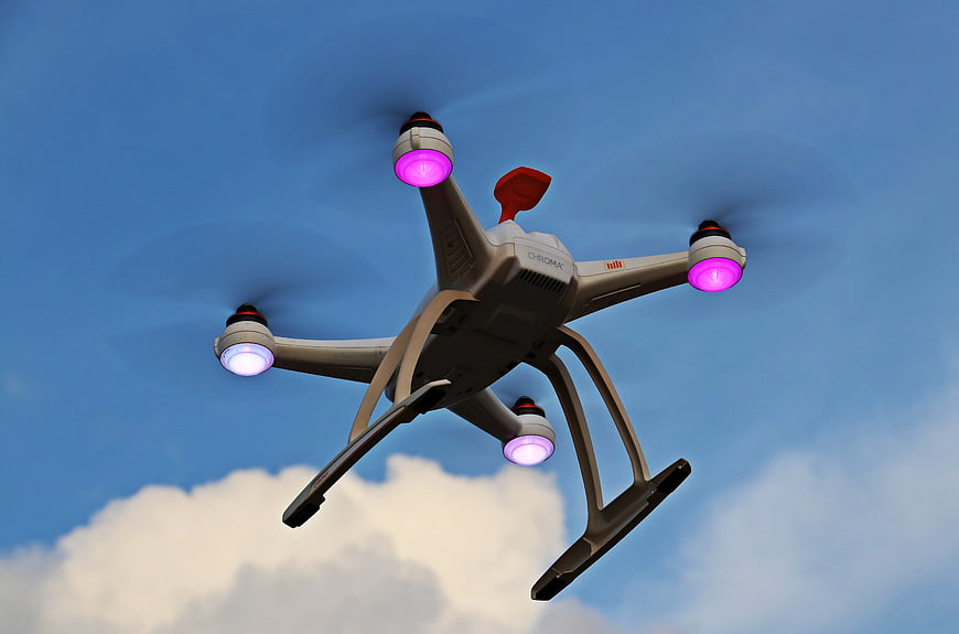 White Quadcopter Drone Flying Against Blue Sky