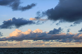 Dramatic sunset clouds over calm ocean horizon