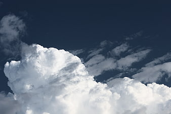 Dramatic white cumulus clouds against deep blue sky