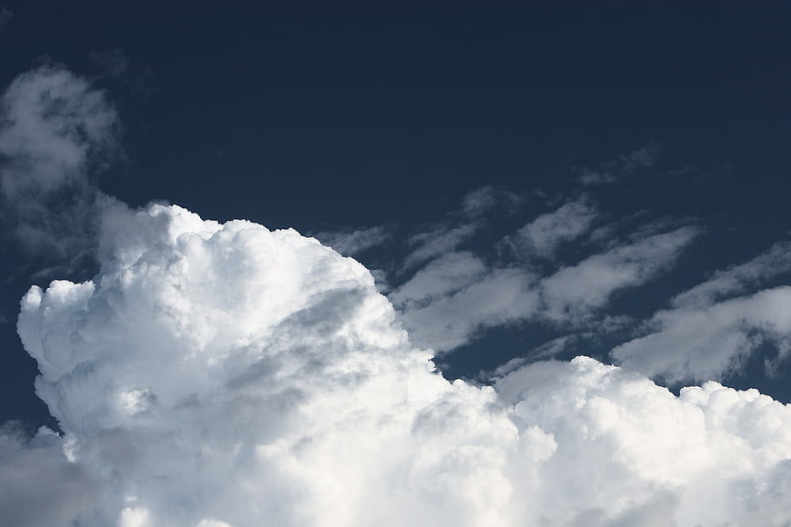 Dramatic white cumulus clouds against deep blue sky