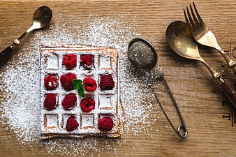 Top view of waffle with raspberries and powdered sugar on wood