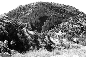 Black and white photo of rocky mountain with cave