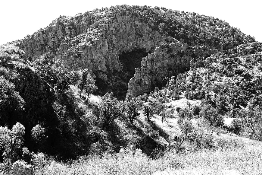 Black and white photo of rocky mountain with cave