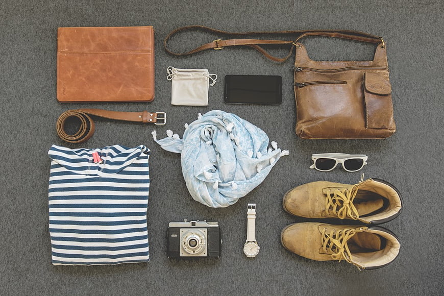 Flat lay of travel accessories, camera, and striped shirt