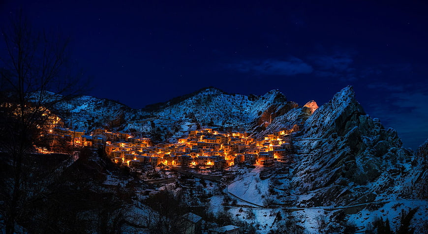 Snowy Mountain Village at Night with Warm Lights