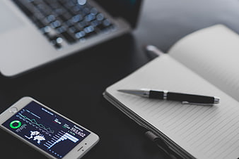 Smartphone Analytics Dashboard on Desk with Laptop and Notepad