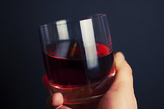 Hand Holding Glass of Red Wine on Dark Background