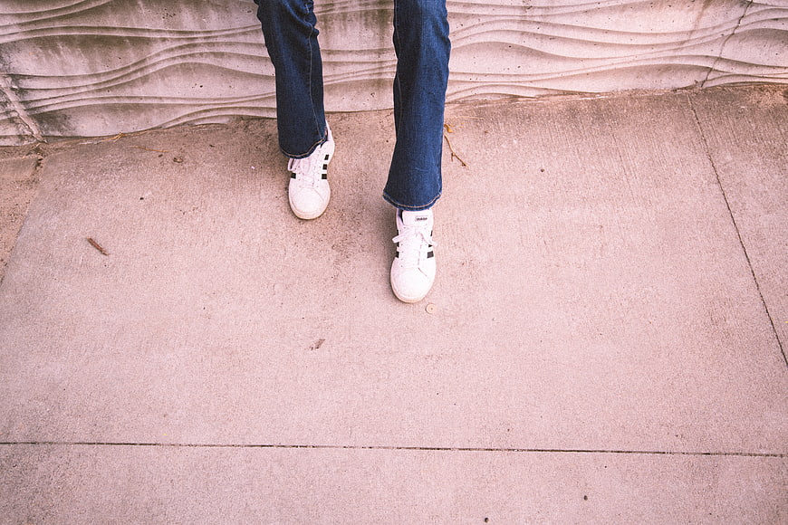 High Angle View of White Sneakers and Jeans on Concrete