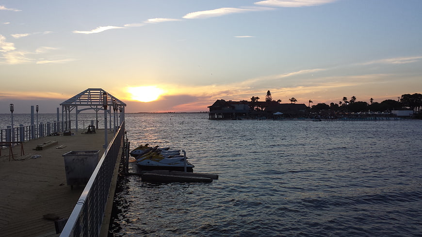 Sunset over a waterfront pier with jet skis and a stilted building