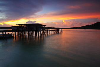 Stilt house pier at sunset with vibrant orange sky