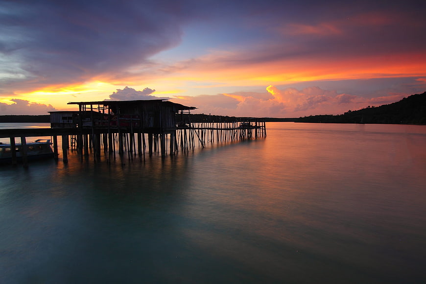 Stilt house pier at sunset with vibrant orange sky
