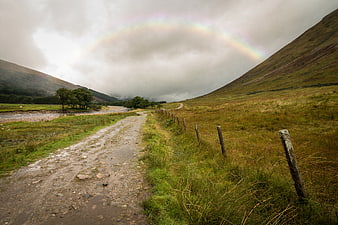 Faint Rainbow Over Muddy Highland Road and Green Hills