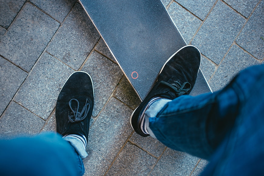 First-person view of feet on skateboard on pavement