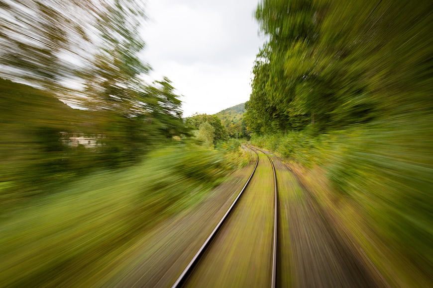 Motion blur railway tracks curving through green forest landscape