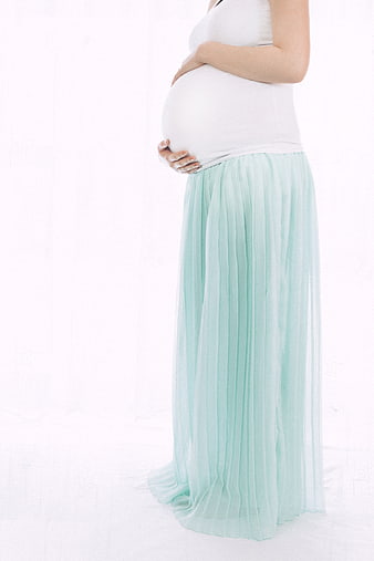 Pregnant woman holding belly in mint skirt