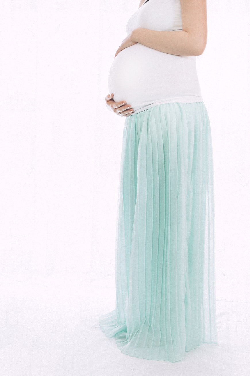 Pregnant woman holding belly in mint skirt