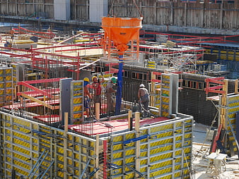 Construction workers pouring concrete with crane hopper