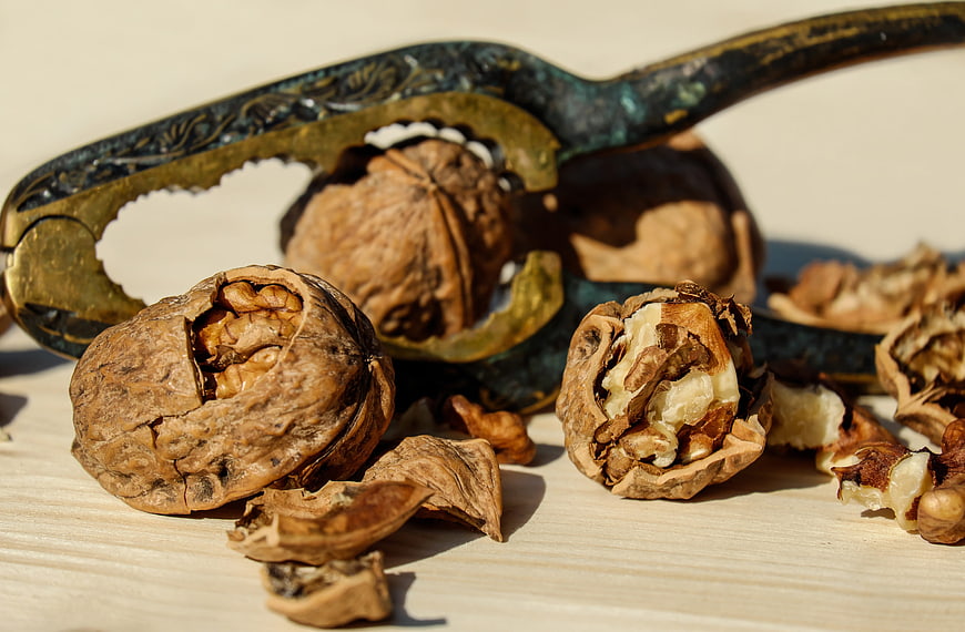 Cracked Walnuts and Vintage Nutcracker on Wooden Surface