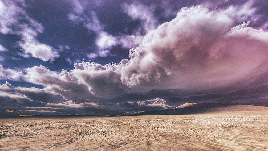 Dramatic purple clouds over vast desert landscape