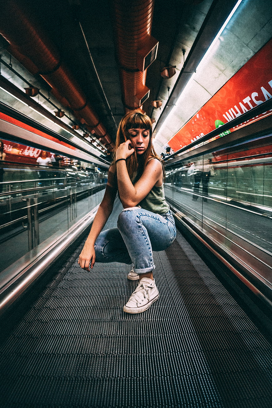 Young woman crouching on moving walkway in subway station