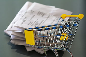Miniature Shopping Cart on Stack of Paper Receipts