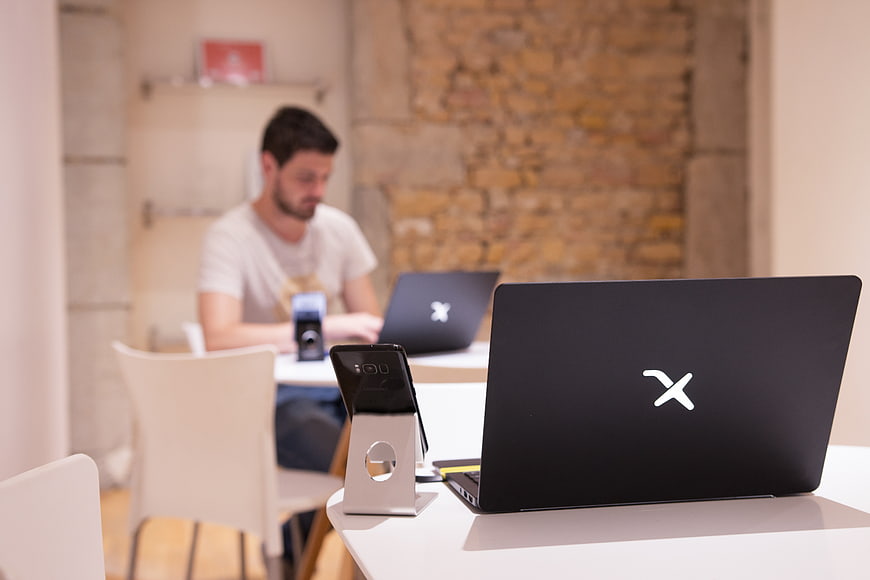 Black laptop and smartphone on white desk in modern office