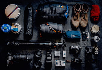 Flat lay of outdoor photography and camping gear on dark background