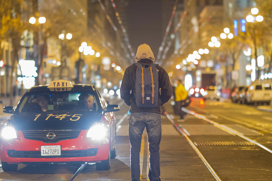 Man with Backpack Standing on City Street at Night
