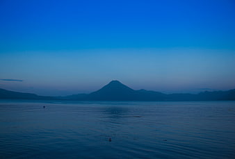 Serene Blue Lake View with Distant Mountain Silhouette at Dusk