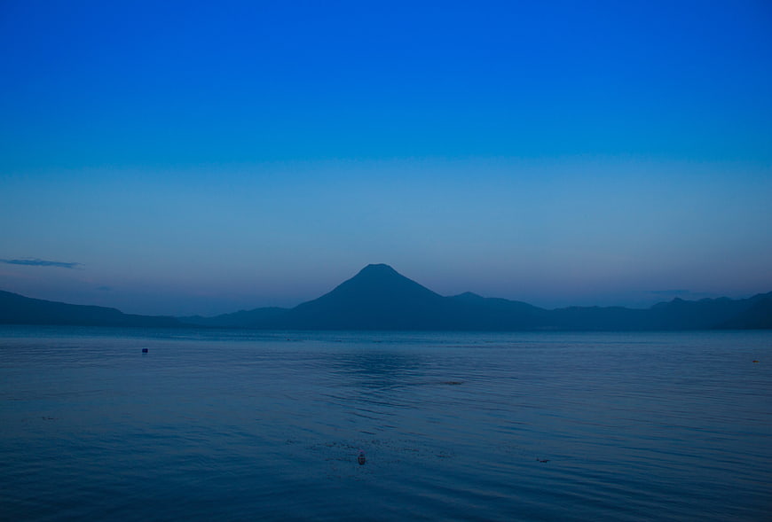 Serene Blue Lake View with Distant Mountain Silhouette at Dusk