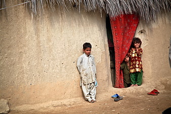Afghan Children Standing Outside Traditional Mud House