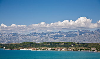Coastal village with turquoise sea and snow-capped mountains