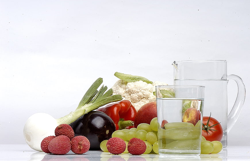 Fresh Fruits, Vegetables, and Water Pitcher on White Background