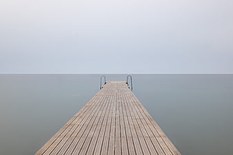 Minimalist Wooden Pier Extending into Calm Foggy Sea